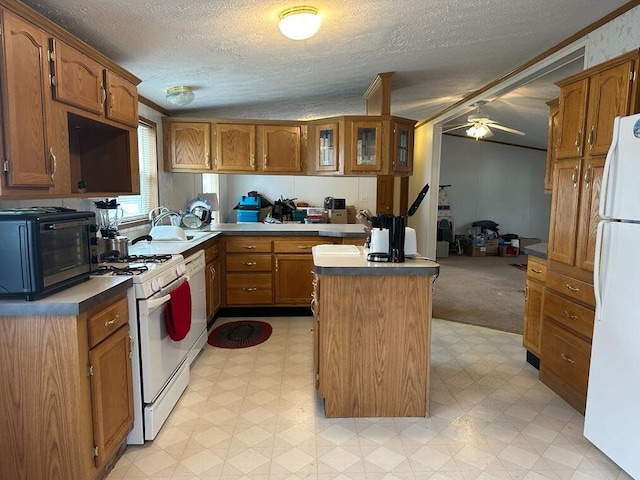 kitchen with sink, ceiling fan, a textured ceiling, white appliances, and a kitchen island