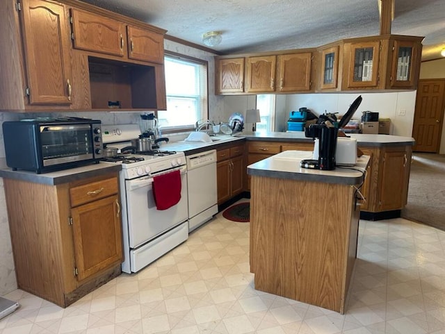 kitchen featuring a kitchen island, a textured ceiling, white appliances, sink, and kitchen peninsula