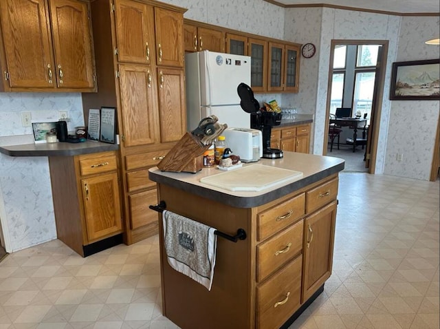 kitchen featuring ornamental molding, a center island, and white fridge