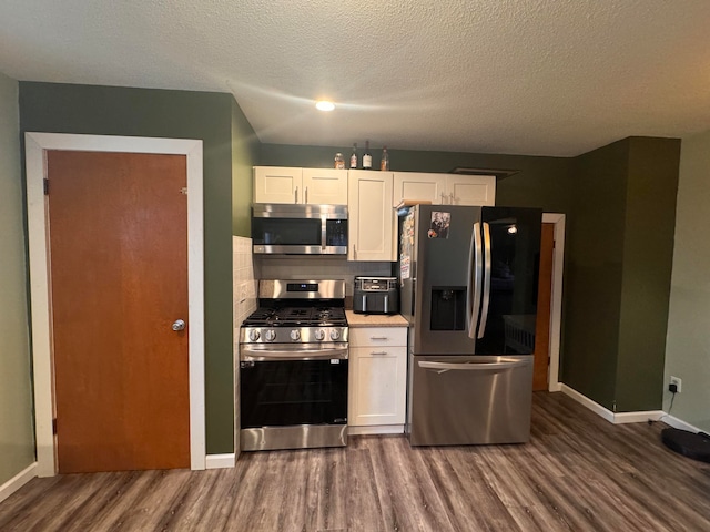 kitchen featuring stainless steel appliances, white cabinetry, a textured ceiling, dark hardwood / wood-style floors, and decorative backsplash