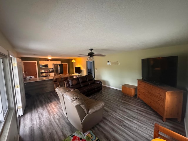 living room featuring dark wood-type flooring, sink, a textured ceiling, and ceiling fan