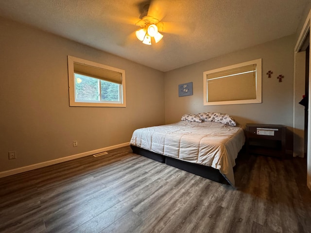 bedroom featuring dark wood-type flooring, a textured ceiling, and ceiling fan