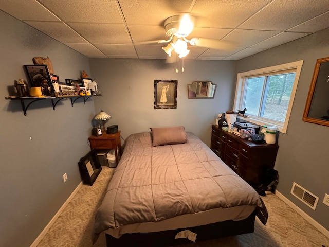 carpeted bedroom featuring ceiling fan and a paneled ceiling