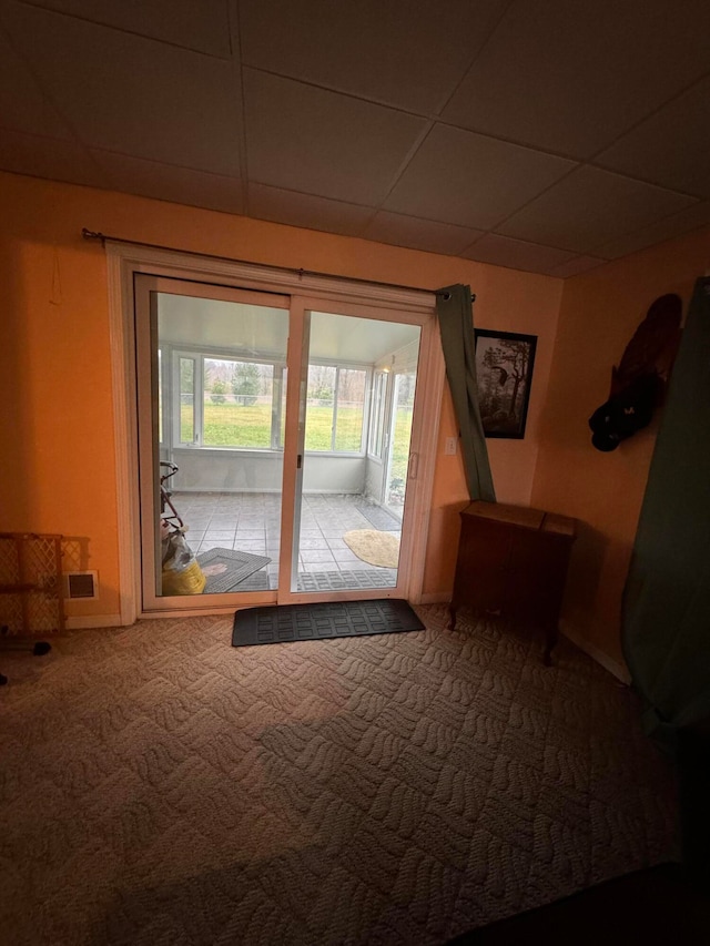 doorway to outside with carpet floors and a drop ceiling