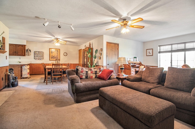 living room with a textured ceiling, light colored carpet, and ceiling fan