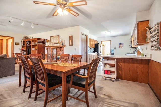 carpeted dining area featuring track lighting, ceiling fan, and sink