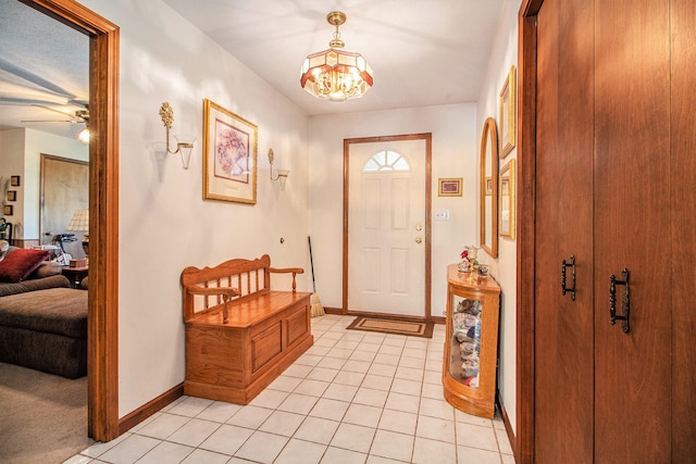 tiled foyer entrance with ceiling fan with notable chandelier