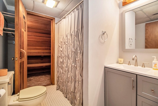 bathroom with tile patterned flooring, a drop ceiling, a shower with curtain, vanity, and toilet