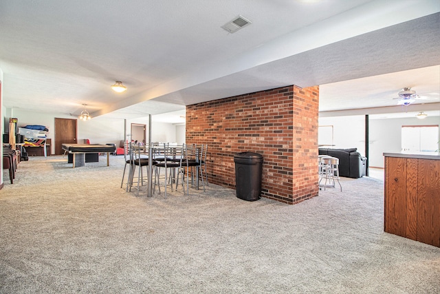 dining room with ceiling fan, a textured ceiling, carpet flooring, and a wood stove