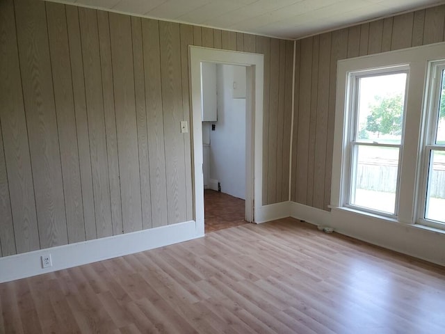 empty room with light hardwood / wood-style flooring, wood walls, and wooden ceiling