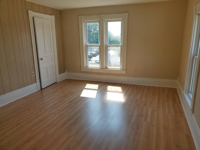 unfurnished room featuring light wood-type flooring and wood walls