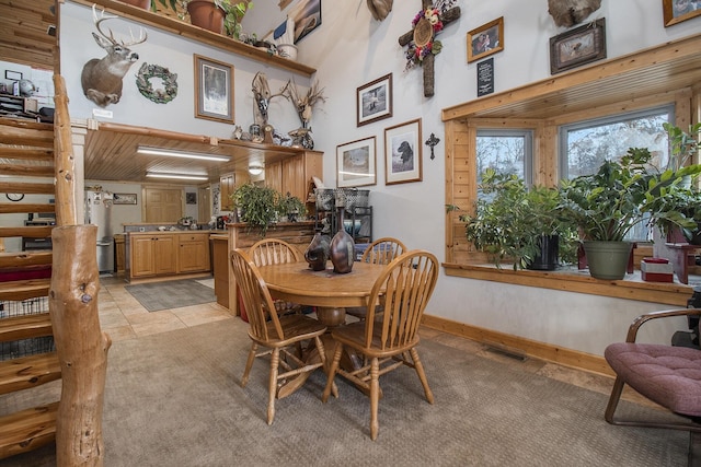 tiled dining area featuring wooden ceiling and a towering ceiling