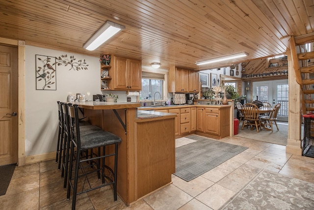 kitchen featuring kitchen peninsula, a breakfast bar area, and wood ceiling