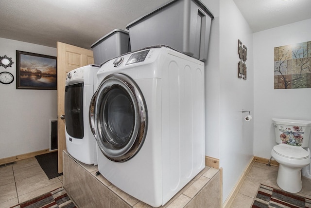 laundry area featuring light tile patterned floors, a textured ceiling, and washing machine and clothes dryer