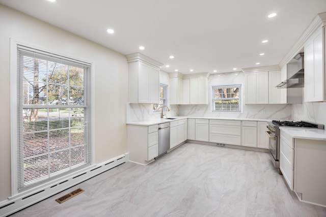 kitchen featuring a wealth of natural light, white cabinetry, appliances with stainless steel finishes, and a baseboard heating unit