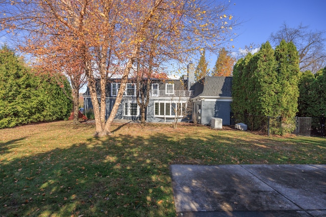 back of house with a lawn and a balcony