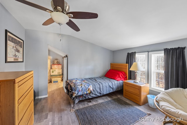 bedroom with vaulted ceiling, ceiling fan, and dark wood-type flooring