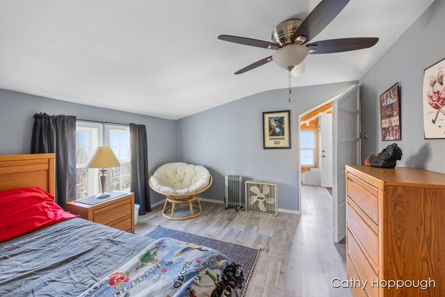 bedroom featuring ceiling fan, radiator heating unit, lofted ceiling, and light wood-type flooring