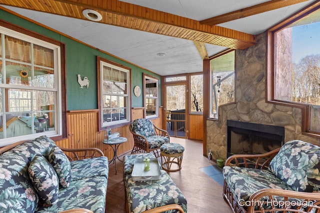 sunroom featuring wood ceiling, a stone fireplace, lofted ceiling with beams, and a healthy amount of sunlight