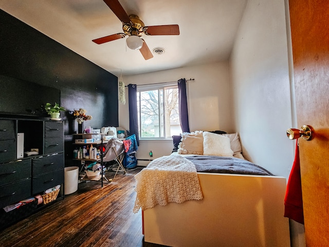 bedroom featuring ceiling fan, a baseboard heating unit, and dark hardwood / wood-style flooring