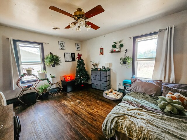 bedroom with dark wood-type flooring, multiple windows, and ceiling fan