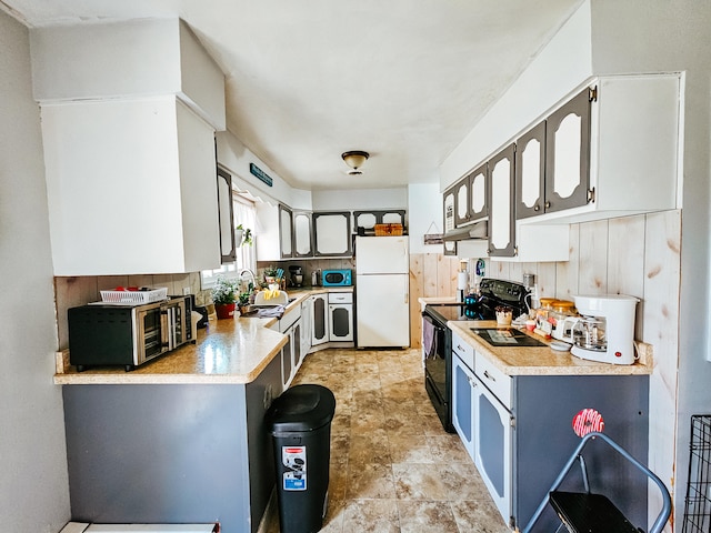 kitchen with ventilation hood, white fridge, white cabinetry, sink, and black / electric stove