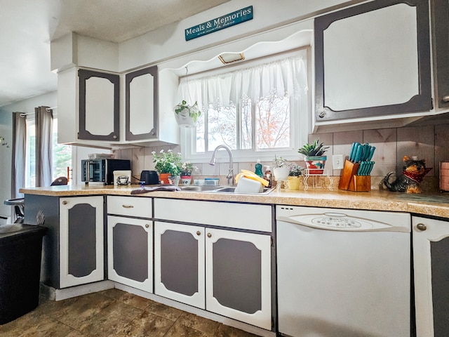 kitchen featuring decorative backsplash, sink, and white dishwasher