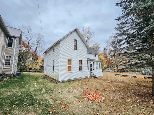 rear view of house featuring cooling unit and a lawn