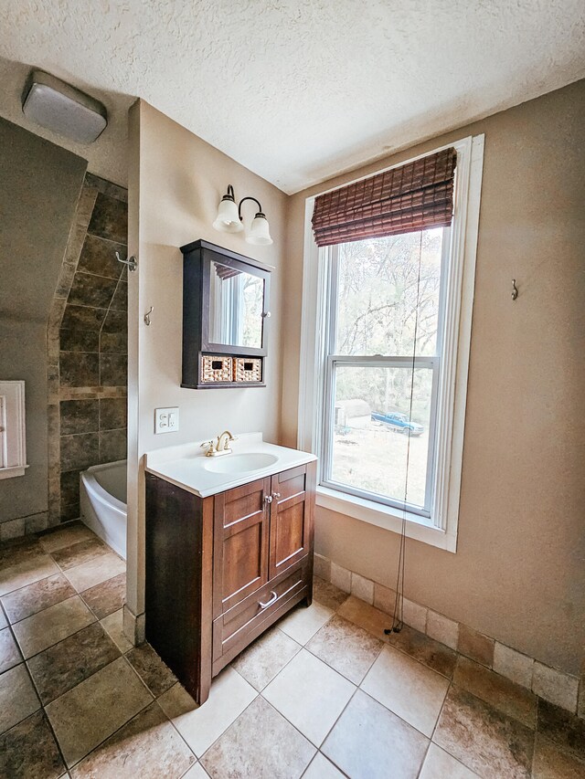 bathroom with tiled shower / bath, vanity, and a textured ceiling