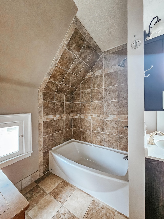 bathroom featuring a bathtub, lofted ceiling, and a textured ceiling