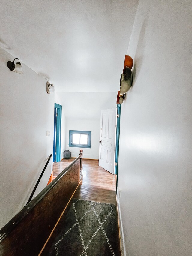 corridor with vaulted ceiling and hardwood / wood-style flooring