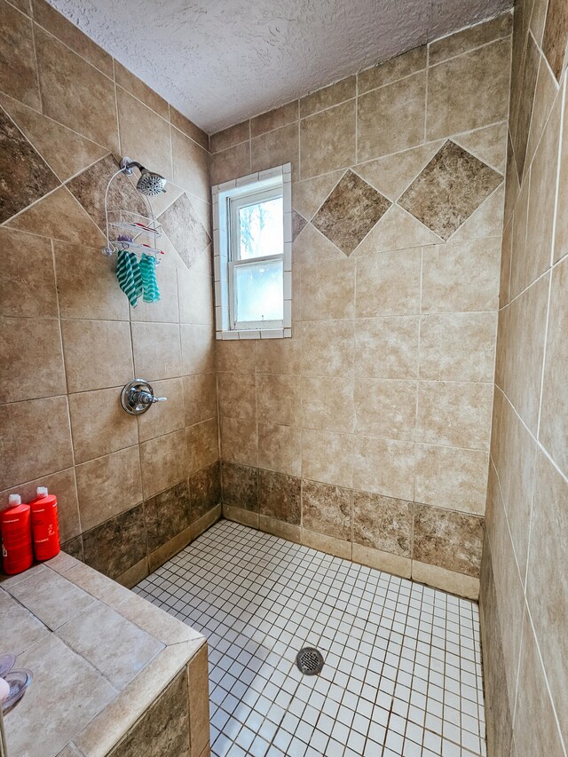 bathroom featuring a textured ceiling, tile patterned floors, and a tile shower