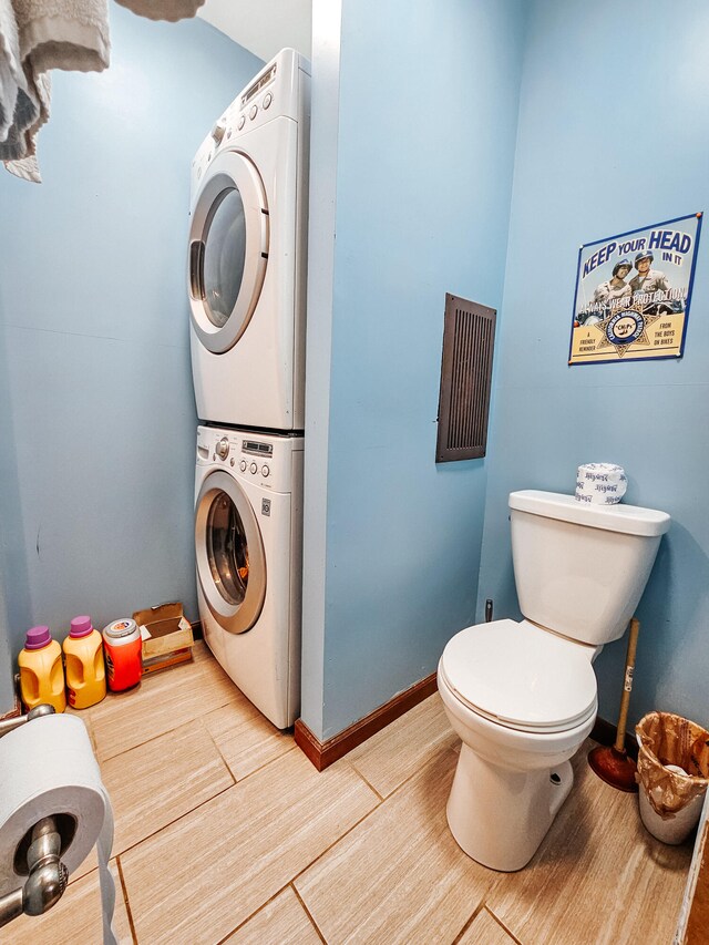 laundry room with stacked washer and dryer and hardwood / wood-style flooring