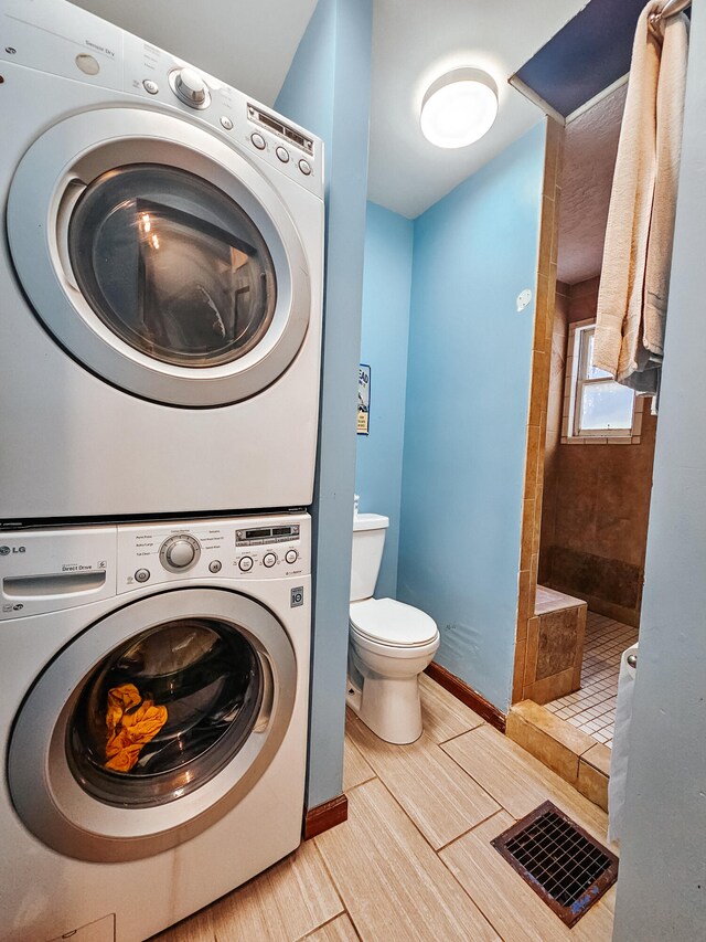 laundry area with light tile patterned floors and stacked washer / dryer