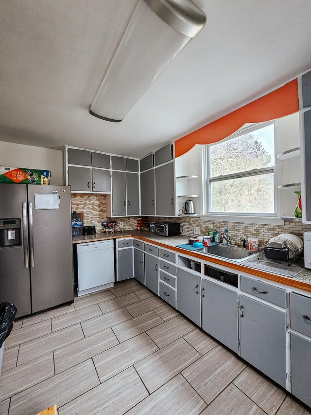 kitchen featuring gray cabinetry, sink, white dishwasher, and stainless steel fridge with ice dispenser