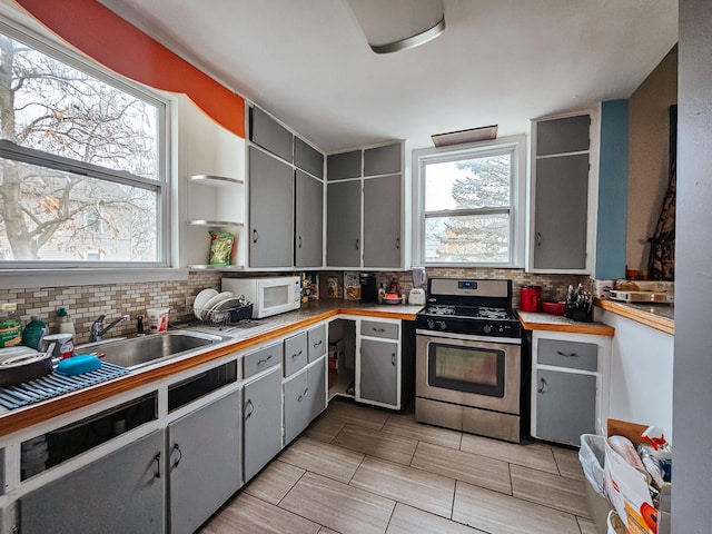 kitchen featuring stainless steel gas range, gray cabinetry, sink, and tasteful backsplash