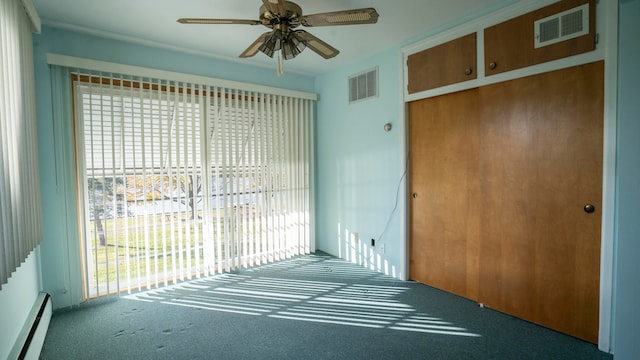 carpeted empty room with baseboard heating, plenty of natural light, and ceiling fan