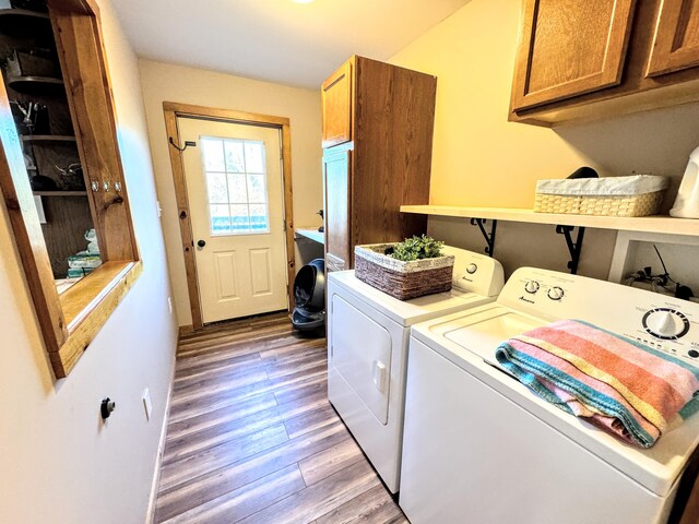 clothes washing area with hardwood / wood-style floors, washer and clothes dryer, and cabinets