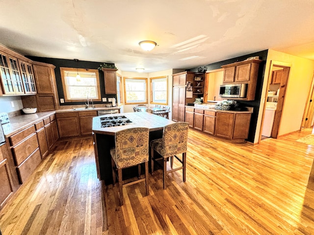 kitchen featuring a kitchen island, light wood-type flooring, appliances with stainless steel finishes, sink, and a breakfast bar