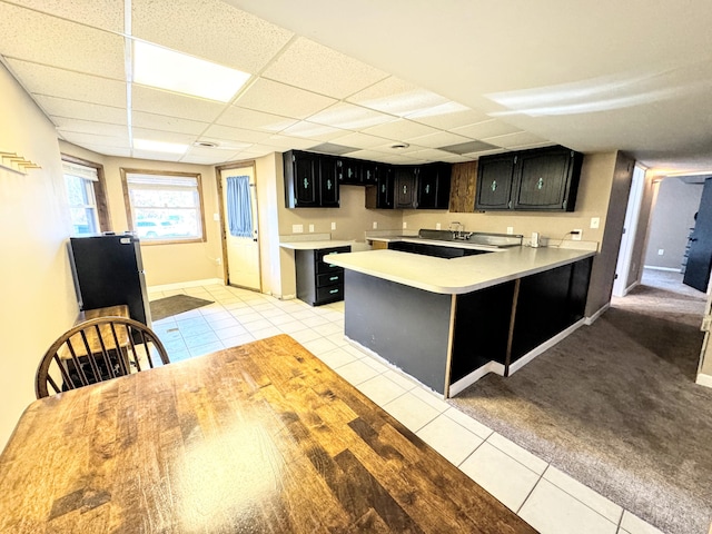 kitchen with a paneled ceiling, kitchen peninsula, and light tile patterned floors