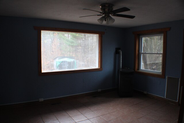 tiled empty room featuring ceiling fan