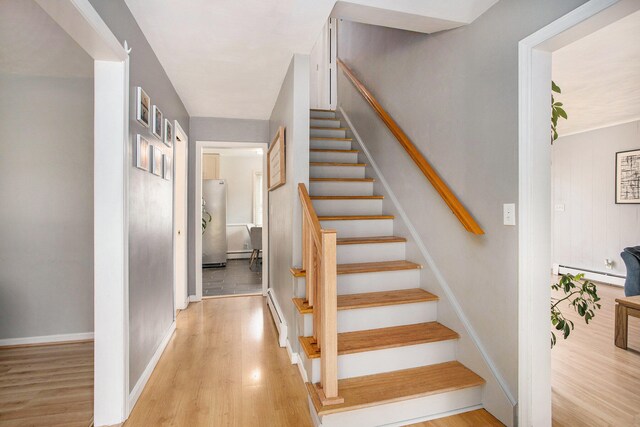 stairs with hardwood / wood-style flooring and a baseboard heating unit