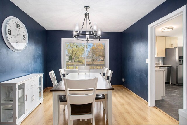 dining area with light hardwood / wood-style floors and an inviting chandelier