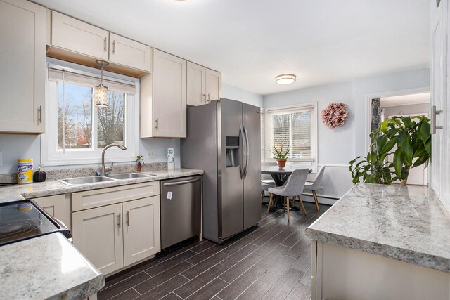 kitchen with stainless steel appliances, dark wood-type flooring, white cabinets, sink, and pendant lighting