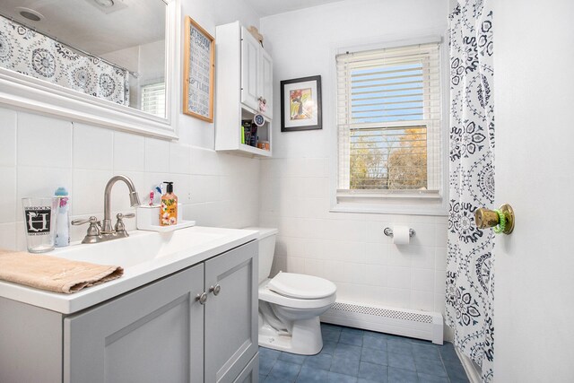 bathroom with a wealth of natural light, baseboard heating, vanity, and toilet