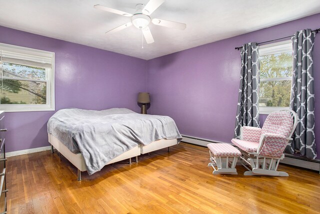 bedroom featuring multiple windows, hardwood / wood-style floors, and ceiling fan