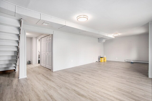 empty room with light wood-type flooring and a baseboard heating unit