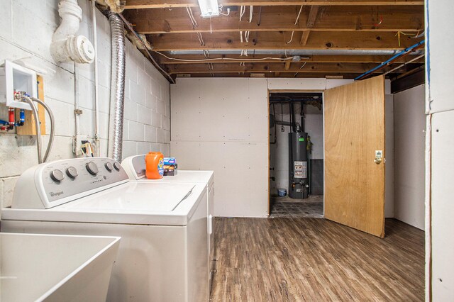 washroom with washing machine and clothes dryer, gas water heater, sink, and hardwood / wood-style floors