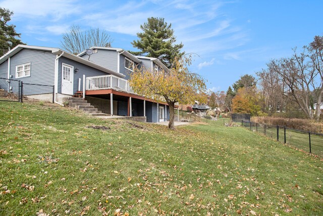 rear view of house with a wooden deck and a lawn