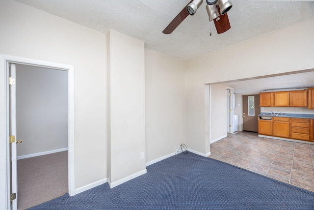 interior space with a textured ceiling, light colored carpet, ceiling fan, and sink